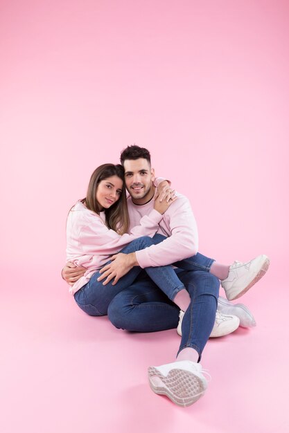 Casal feliz abraçando no fundo rosa