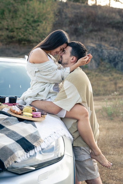 Casal feliz aproveita um fim de semana de verão com um carro fora da cidade em um campo