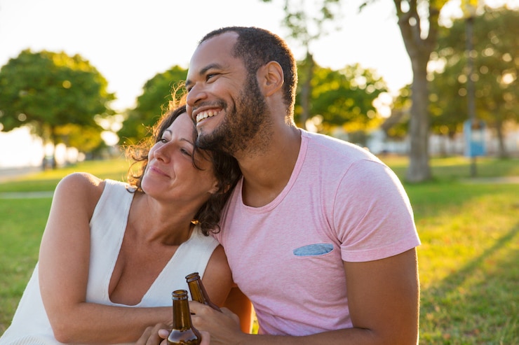 Foto grátis casal feliz, aproveitando o encontro ao ar livre ao pôr do sol