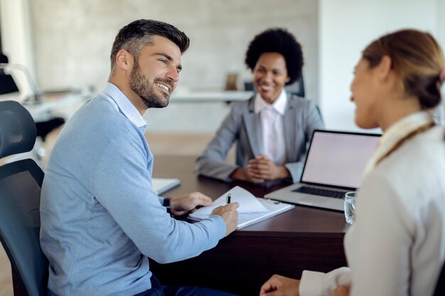 Casal feliz assinando contrato de hipoteca em uma reunião com agente imobiliário