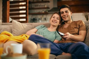 Casal feliz assistindo filme enquanto relaxa no sofá em casa