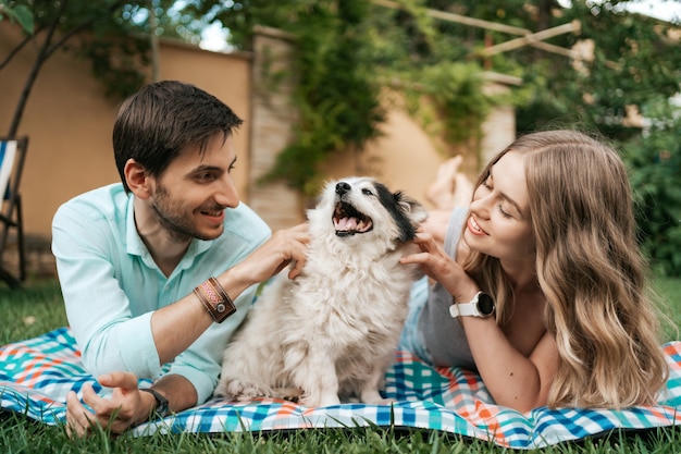 Casal feliz brincando com seu cachorro no quintal na grama. cachorro velho alegre