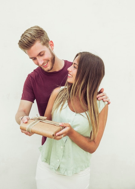 Casal feliz com presente de aniversário na frente da parede