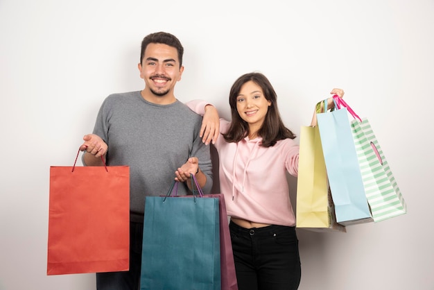 Foto grátis casal feliz com sacolas de compras, posando em branco.