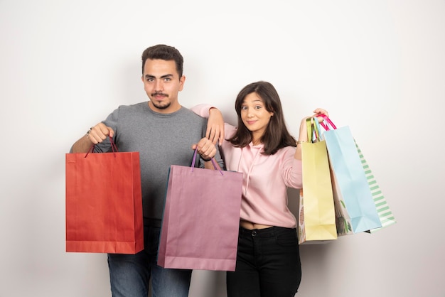 Casal feliz com sacolas de compras posando.