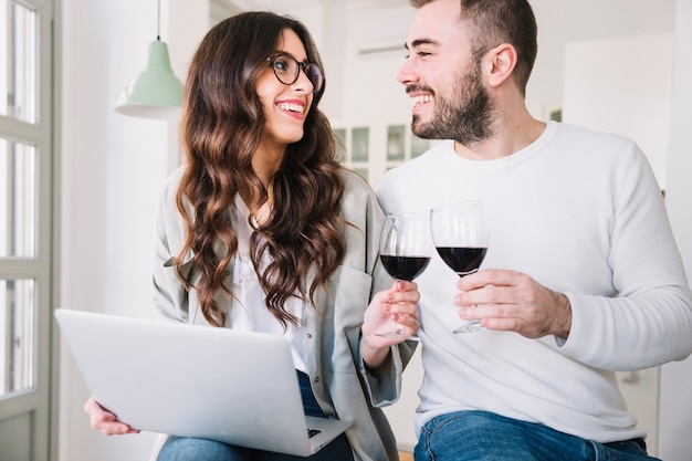 Casal feliz com vinho e laptop