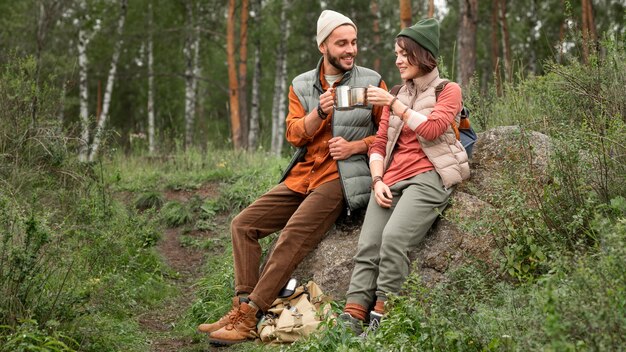 Casal feliz curtindo uma bebida quente na natureza