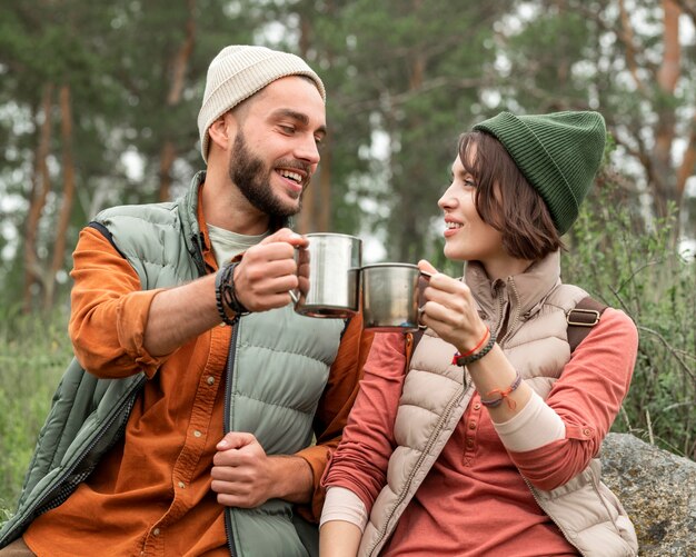 Casal feliz curtindo uma bebida quente na natureza