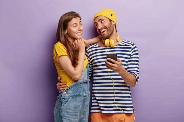 Casal feliz e elegante posando com smartphone