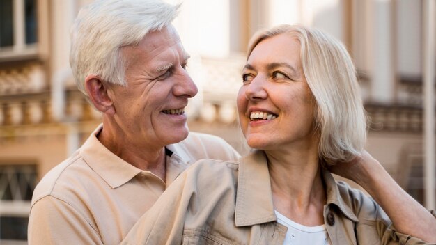 Casal feliz e sorridente se abraçando enquanto se diverte ao ar livre