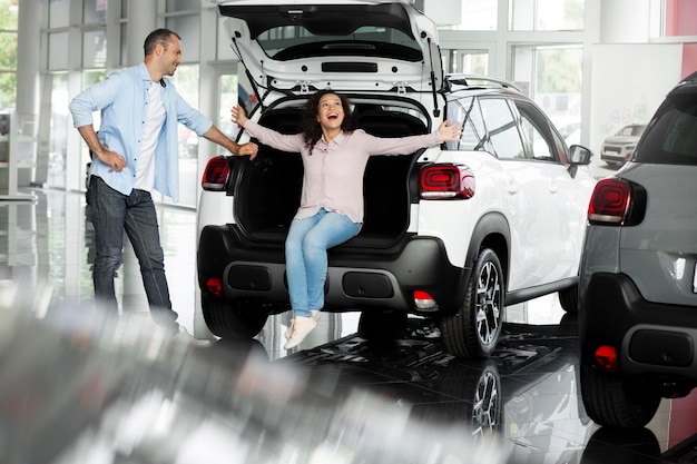 Casal feliz em concessionária de showroom de carros