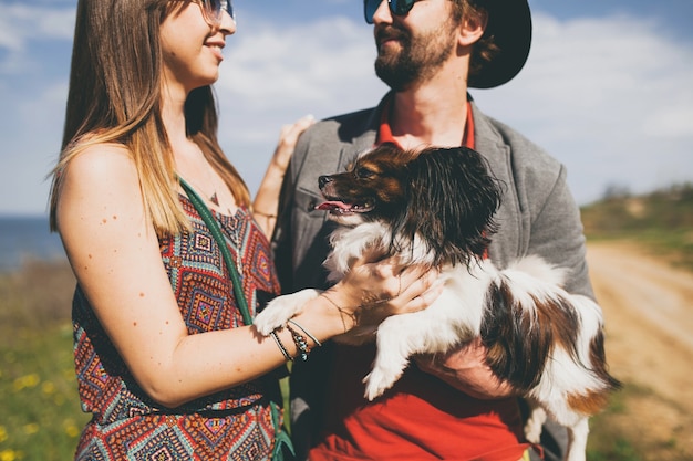 Casal feliz, jovem e elegante hippie apaixonado, caminhando com um cachorro no campo