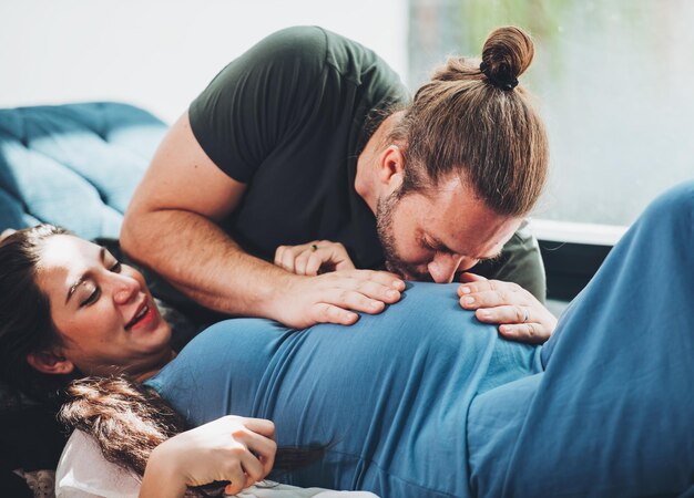 Casal feliz mulher grávida e marido ficam em casa na sala Casal feliz cuidando juntos