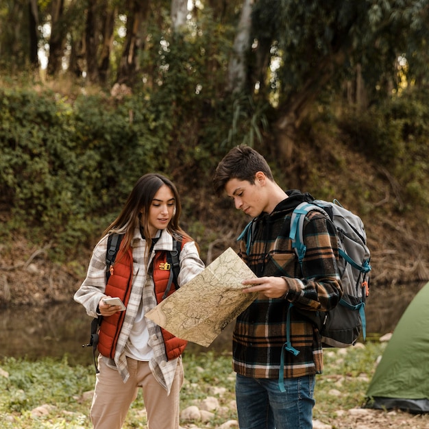 Foto grátis casal feliz na floresta olhando juntos no mapa