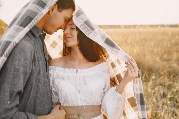 Casal feliz no amor no campo de trigo ao pôr do sol