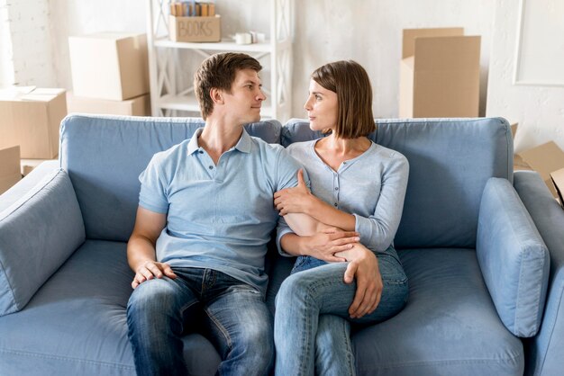 Casal feliz no sofá enquanto faz as malas para mudar de casa