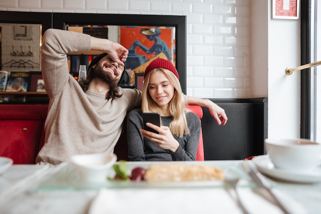 Casal feliz olhando para celular no café