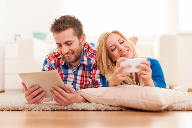 Casal feliz passando um tempo com equipamentos eletrônicos em casa