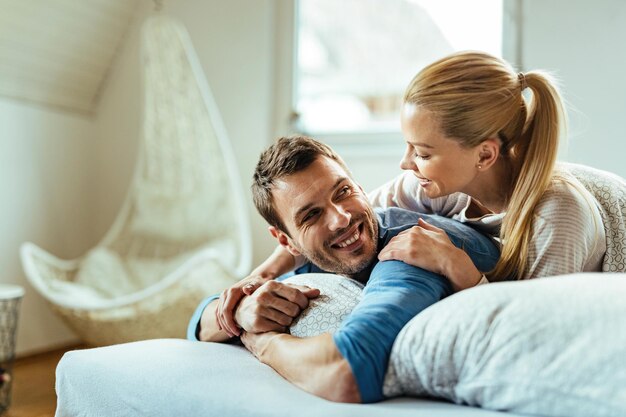 Casal feliz se comunicando enquanto relaxa na cama pela manhã.