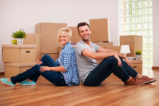 Casal feliz sentado de costas um para o outro em sua nova casa