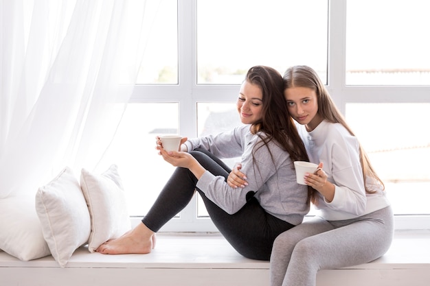 Foto grátis casal feliz sentado na janela com café