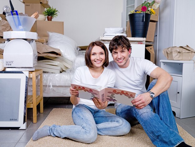 Casal feliz sentado no chão junto com o álbum de fotos