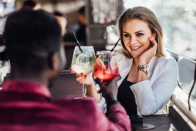 Casal feliz tendo momentos de ternura e bebendo coquetéis no bar do salão - jovens amantes se divertindo namoro em hotel clube de luxo.