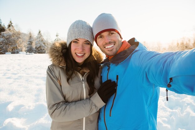 Casal feliz tirando uma selfie em paisagem de neve