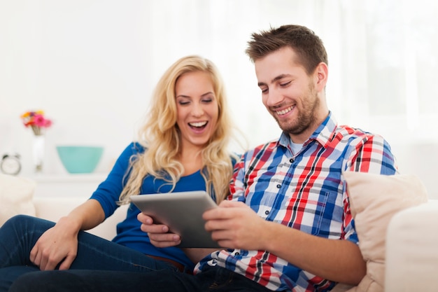 Casal feliz usando tablet digital em casa