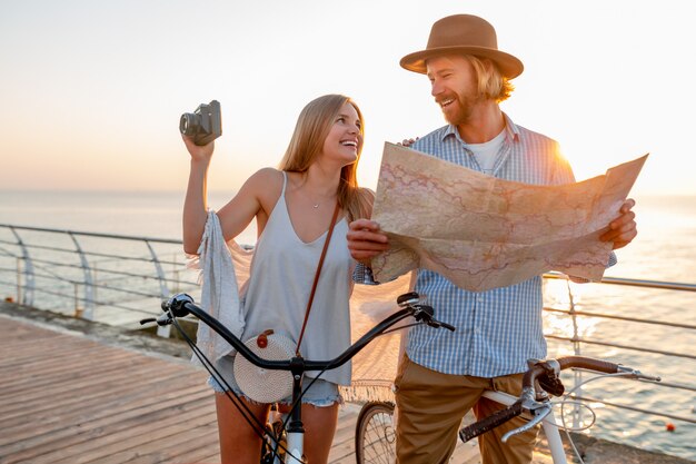 casal feliz viajando no verão de bicicleta, olhando no mapa e tirando fotos