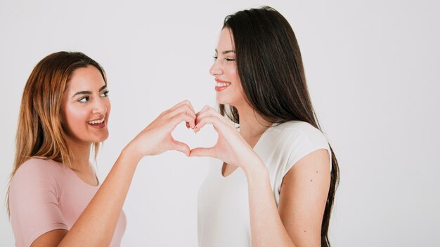 Casal feminino bonito que gesticula o coração