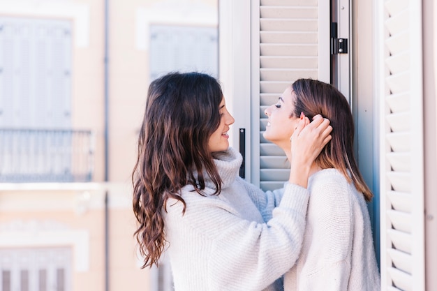 Casal feminino gentil se beijando na varanda