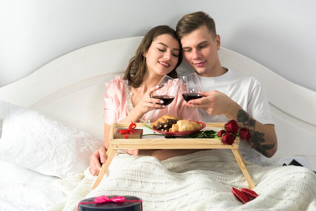 Casal fofo bebendo vinho na cama