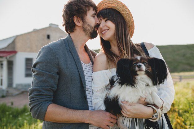 Casal fofo, muito elegante, hipster apaixonado, caminhando com um cachorro no campo