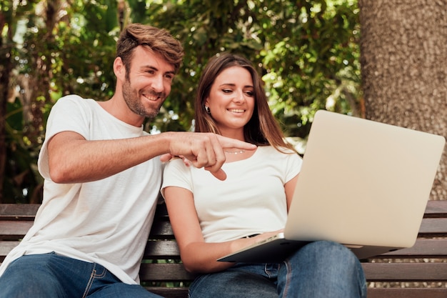 Casal fofo num banco com um notebook