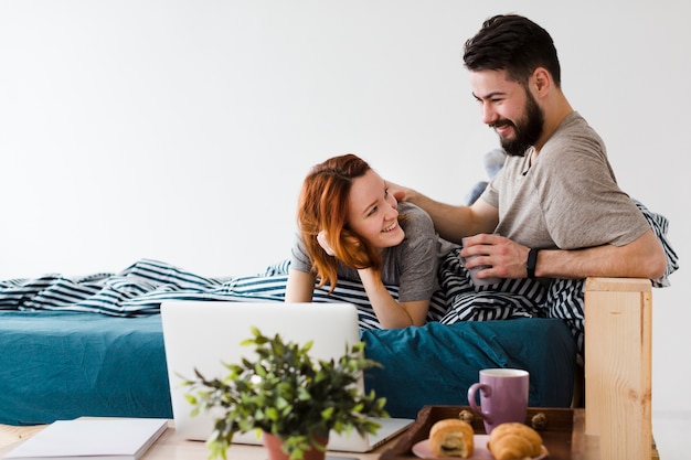 Casal fofo olhando um ao outro e laptop