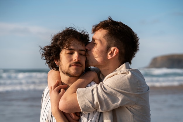 Casal gay de tiro médio na praia