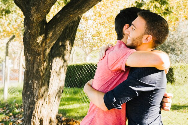 Casal gay feliz abraçando no parque