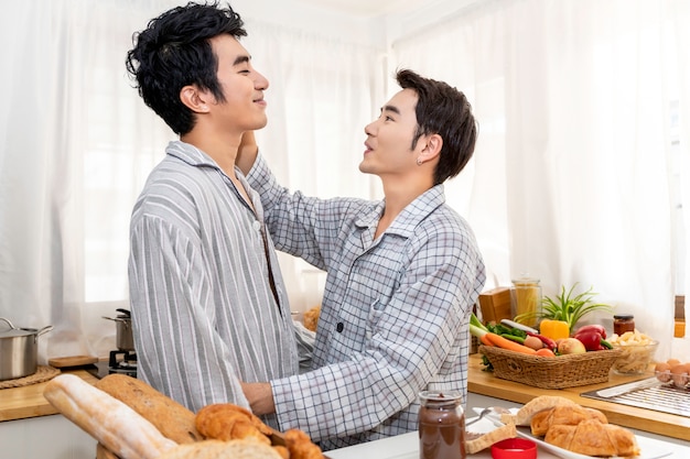 Casal homossexual asiático cozinhando o café da manhã na cozinha pela manhã