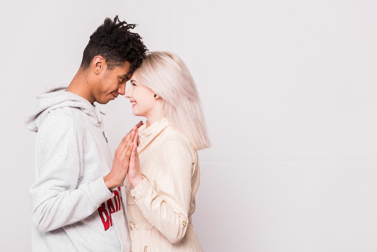Foto grátis casal interracial amoroso olhando uns aos outros e tocando suas palmas