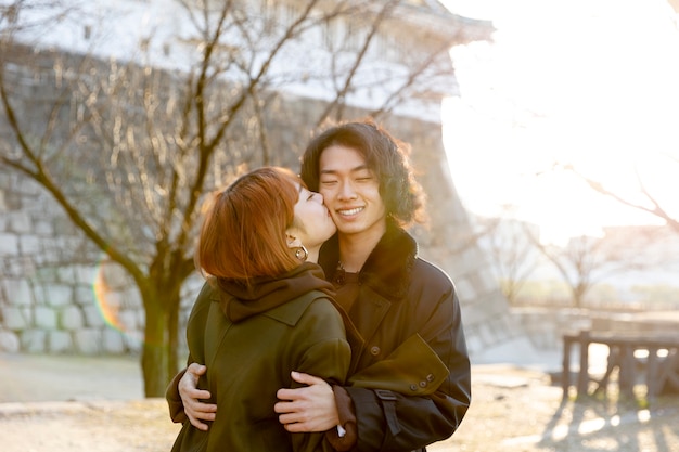 Casal japonês abraçando ao ar livre no dia branco