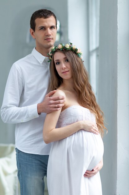 Casal jovem alegre, vestido de branco em pé em casa