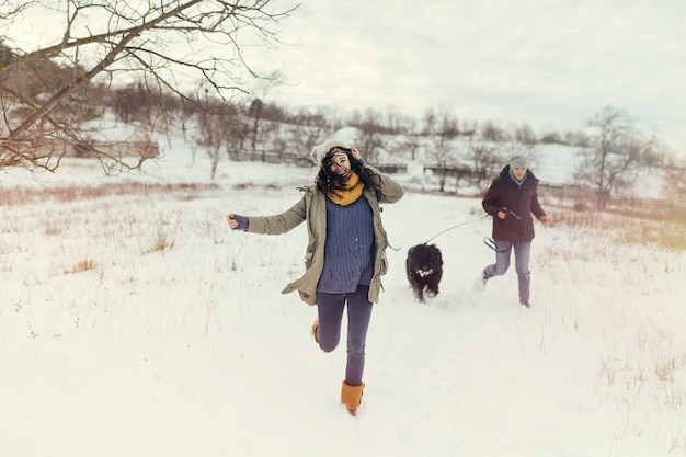 Casal jovem andando com um cachorro em um dia de inverno