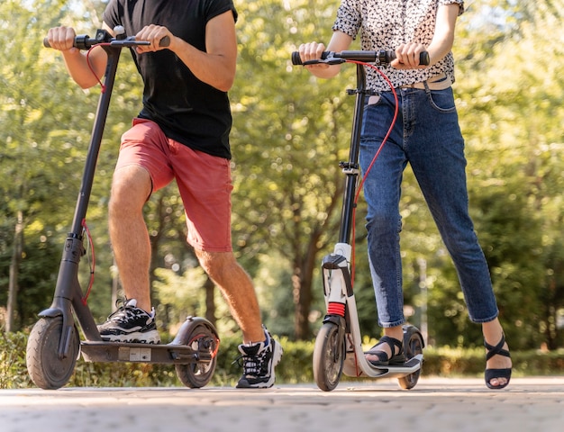 Casal jovem andando de scooters ao ar livre