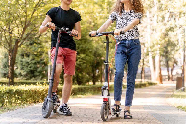 Casal jovem andando de scooters ao ar livre