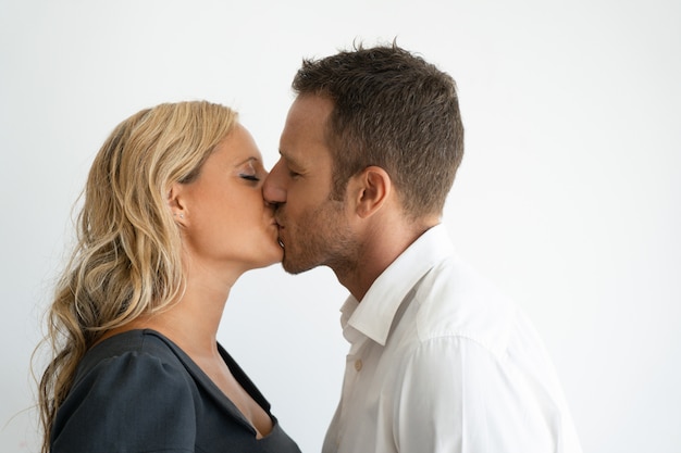 Casal jovem apaixonado beijando com os olhos fechados.