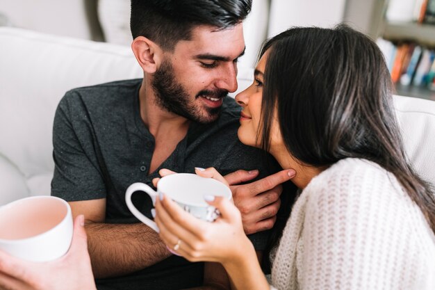 Casal jovem apaixonado olhando uns aos outros segurando a xícara de café