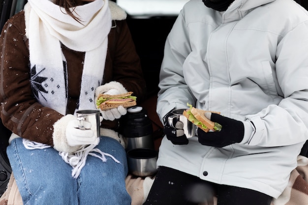 Casal jovem apreciando bebidas quentes e um sanduíche durante uma viagem de inverno