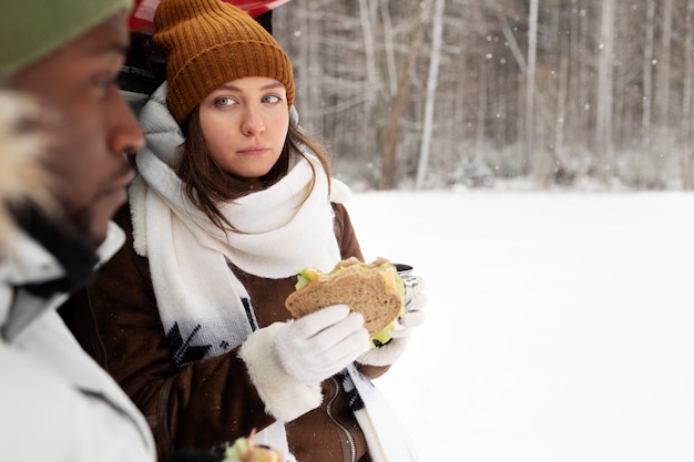 Foto grátis casal jovem apreciando bebidas quentes e um sanduíche durante uma viagem de inverno