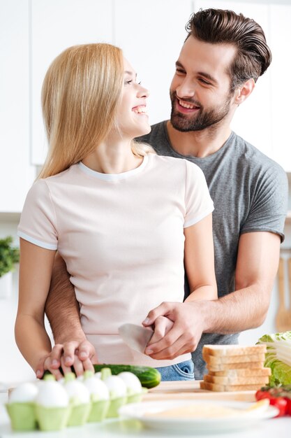 Casal jovem bonito juntos a preparar salada saudável